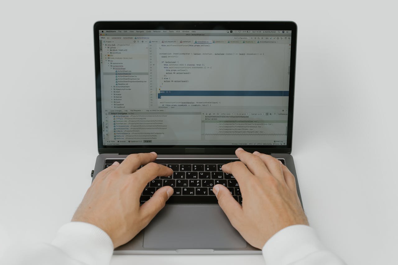Close-up of hands coding on a laptop, showcasing software development in action.